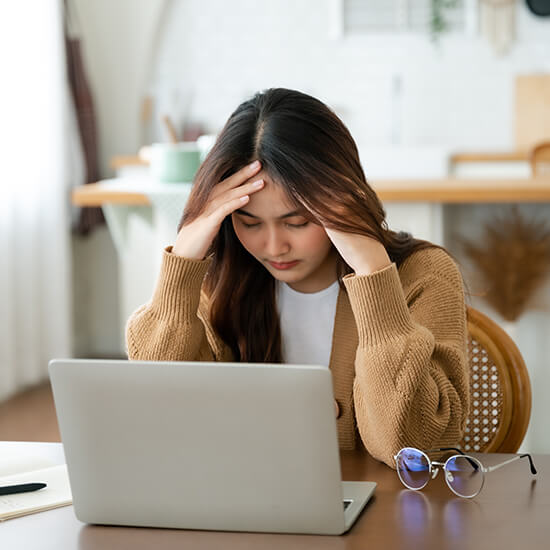 Girl experiencing burnout, sitting stressed in front of a laptop